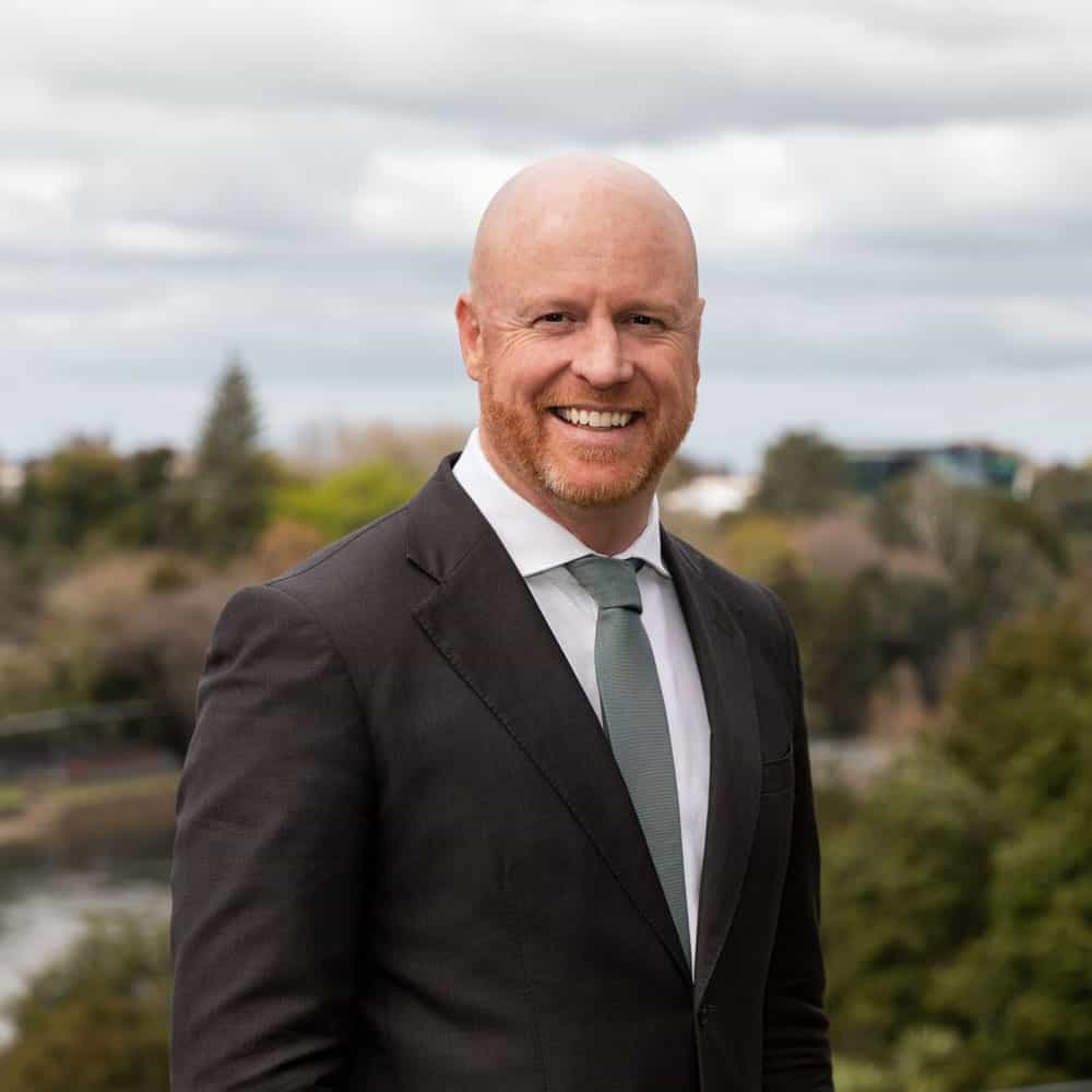 happy male employment lawyer NZ in black suit with grey tie